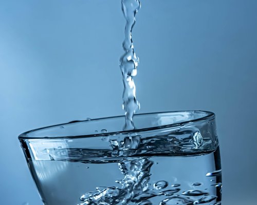 A person pouring clean drinking water into a glass