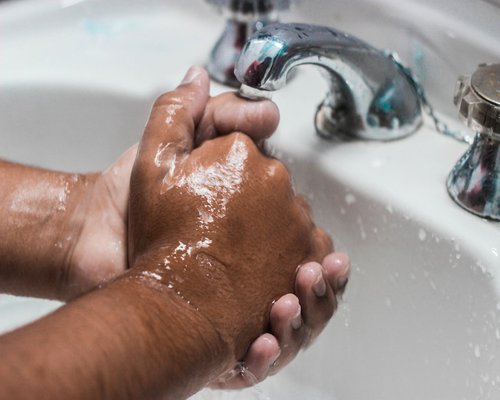 Washing hands thoroughly with soap in a clean sink